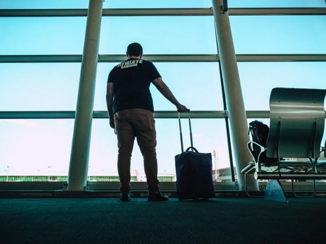 man holding underseat luggage bag