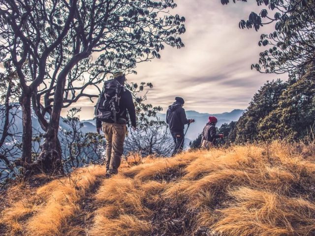 people with backpacks hiking on high mountain