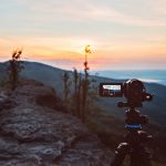 digital camera on tripod filming sunrise at mountains