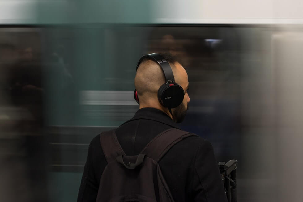 man wearing black headphones in metro station